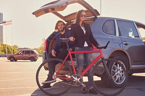 Couple with fixed bicycle near the car — Stock Photo, Image