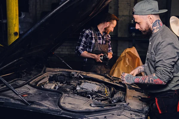 Mecánica tatuada arreglando el motor del coche — Foto de Stock