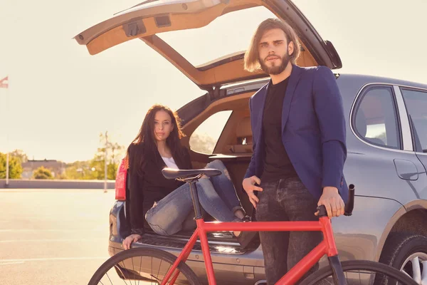 Pareja urbana con bicicleta cerca del coche — Foto de Stock