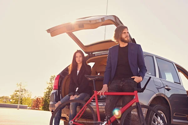 Pareja urbana con bicicleta cerca del coche — Foto de Stock