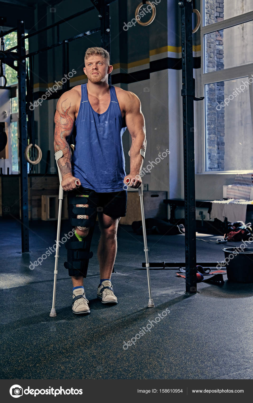 Bodybuilder on crutches in a gym club. Stock Photo by ©fxquadro 158610954