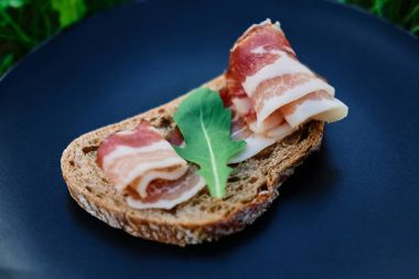 Jambon ve siyah bir plaka üzerinde otlar ile ekmek 