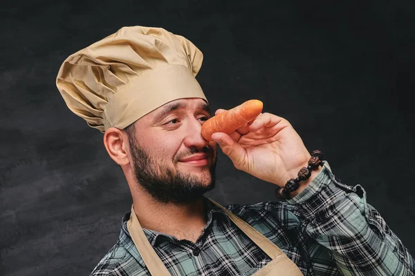 Chef segura cenoura perto de seu nariz — Fotografia de Stock