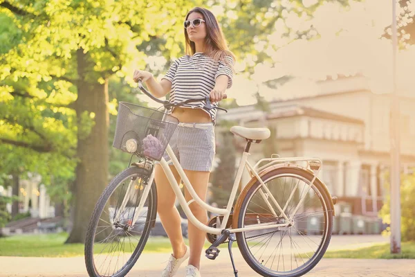 Mujer morena de pie con bicicleta — Foto de Stock