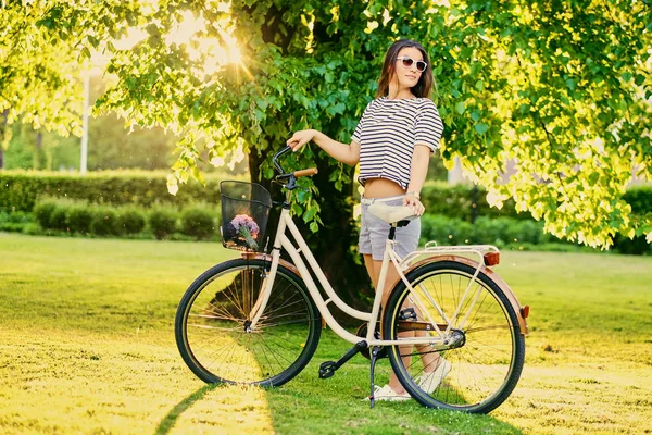 Brunett kvinna står med cykel — Stockfoto