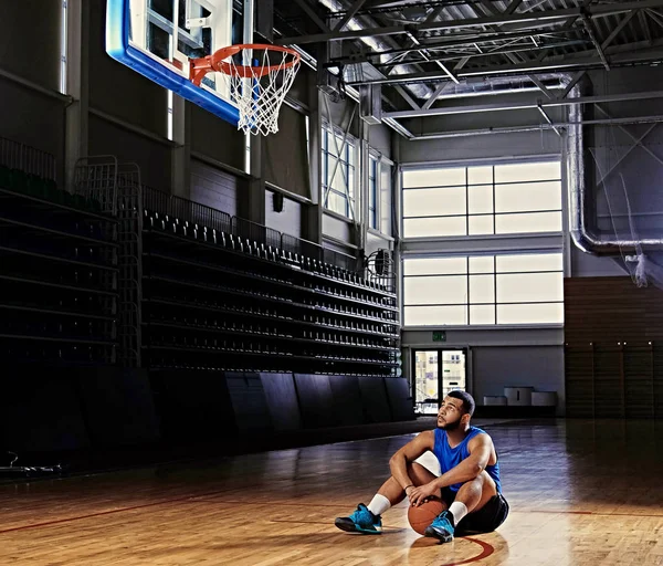 Jugador de baloncesto se sienta en un piso — Foto de Stock