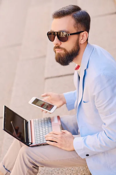 Homem senta-se em um passo e usando laptop — Fotografia de Stock