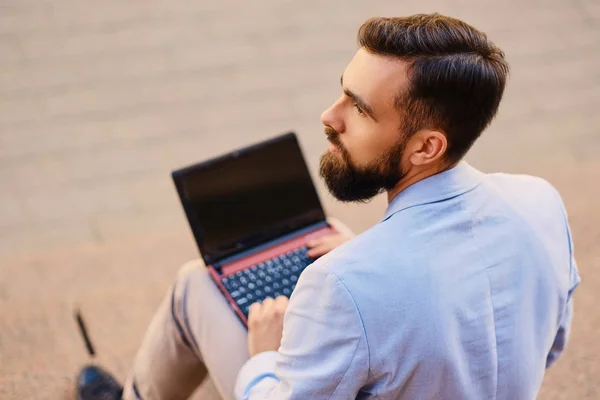 Man sits on a step and using laptop — Stock Photo, Image