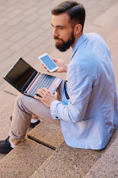 Man sits on a step and using laptop — Stock Photo, Image