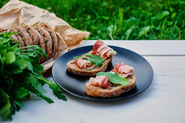 Brood met ham en kruiden op een zwarte plaat — Stockfoto