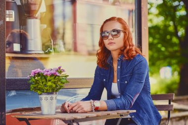 Kızıl saçlı kadın bir sokakta bir kafede