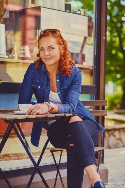 Kızıl saçlı kadın bir kafede kahve içer