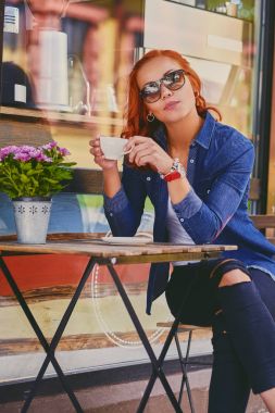 Kızıl saçlı kadın bir kafede kahve içer