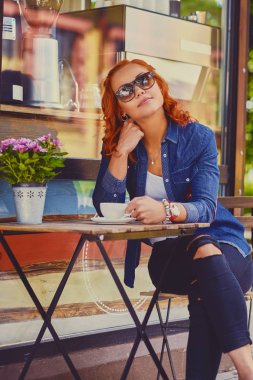 Kızıl saçlı kadın bir kafede kahve içer