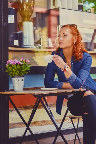 Roodharige vrouw drinkt koffie in een café — Stockfoto