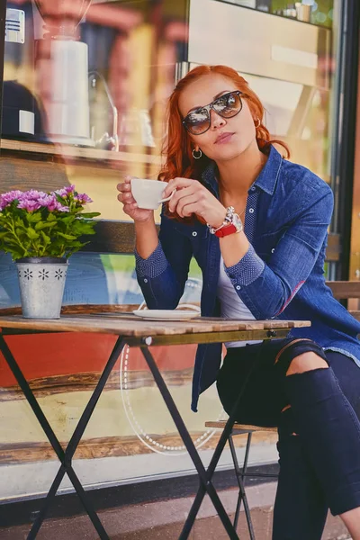 Kızıl saçlı kadın bir kafede kahve içer