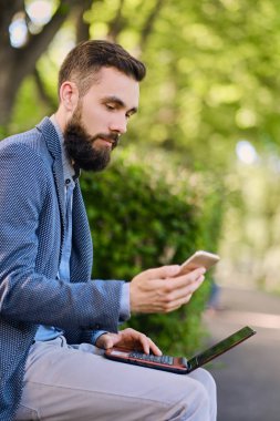 Bir parkta dizüstü bilgisayar kullanan adam
