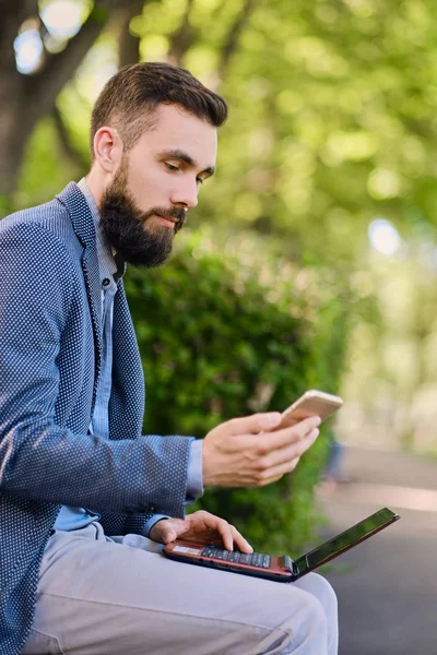 Bir parkta dizüstü bilgisayar kullanan adam