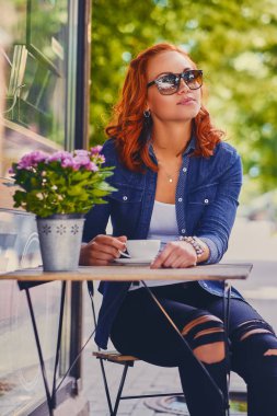 Kızıl saçlı kadın bir kafede kahve içer