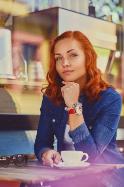 Kızıl saçlı kadın bir kafede kahve içer
