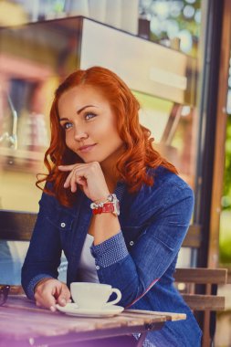 Kızıl saçlı kadın bir kafede kahve içer