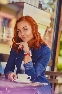 Kızıl saçlı kadın bir kafede kahve içer