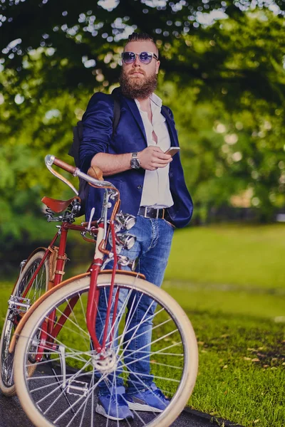 Бородатый мужчина с велосипедом и смартфоном — стоковое фото