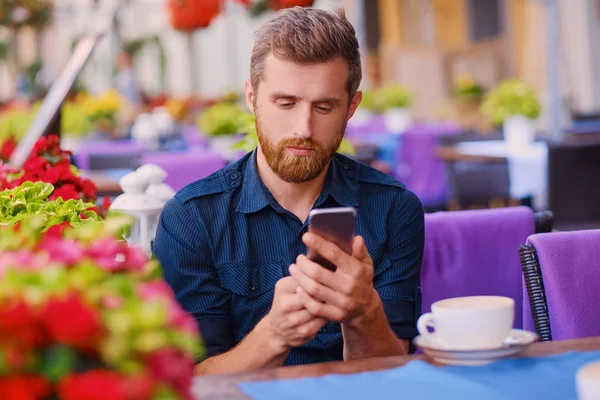 Homem bebe café e usando um smartphone — Fotografia de Stock