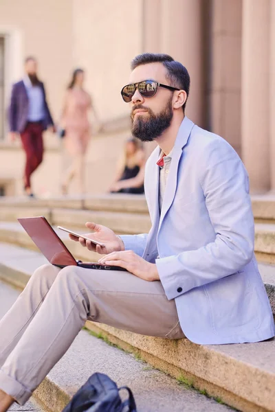 Man sitter på ett steg och använder bärbar dator — Stockfoto