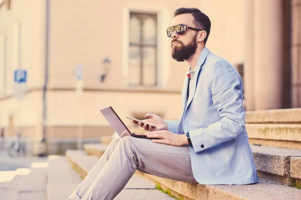 Man sitter på ett steg och använder bärbar dator — Stockfoto