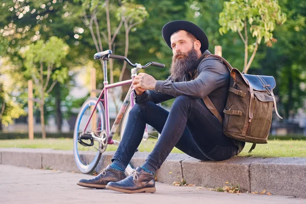 Hipster se sienta en un paso y usando un teléfono inteligente — Foto de Stock