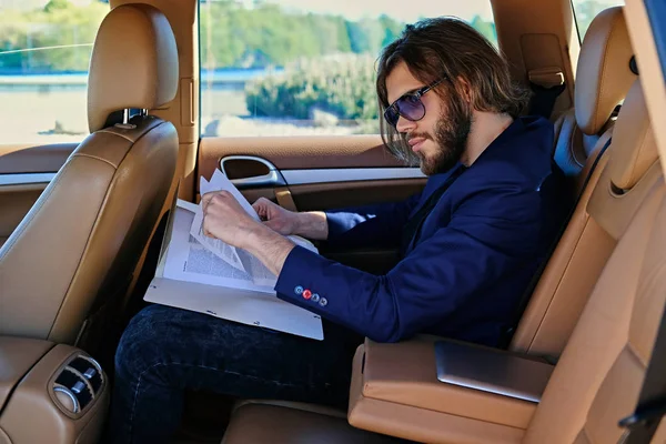 Hombre se sienta en un coche y trabaja con documentos — Foto de Stock