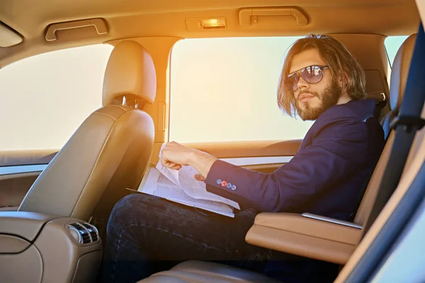 Hombre se sienta en un coche y trabaja con documentos — Foto de Stock