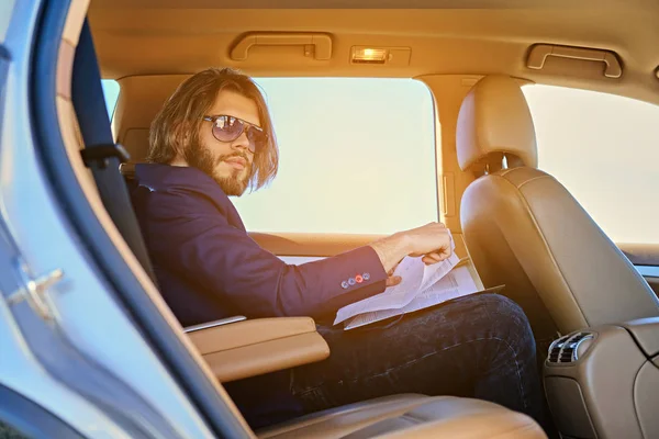 Hombre se sienta en un coche y trabaja con documentos — Foto de Stock