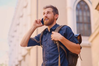 Adam akıllı telefon tarafından konuşan sırt çantası ile