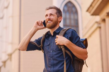 Adam akıllı telefon tarafından konuşan sırt çantası ile