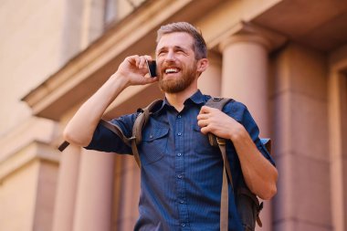 Adam akıllı telefon tarafından konuşan sırt çantası ile