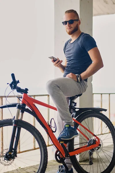 Sakallı sportif erkek bir akıllı telefon tutar