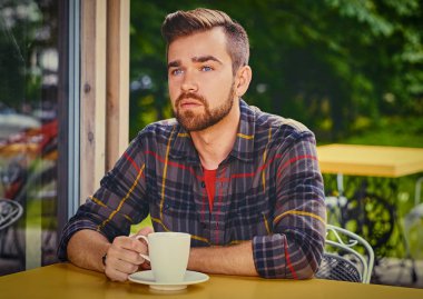 Adam bir kafede kahve içer.