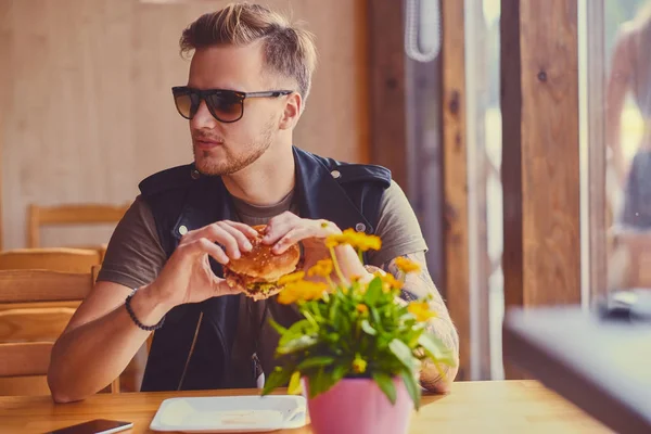 Человек ест веганский бургер в кафе — стоковое фото