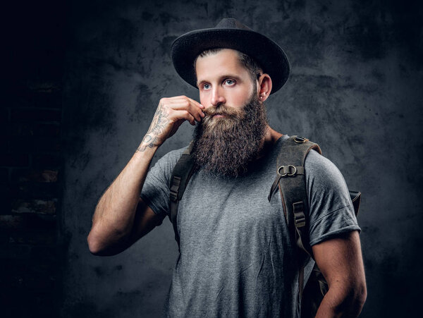 Bearded tattooed male in a hat with a backpack 