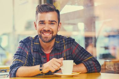 Adam bir kafede kahve içer.