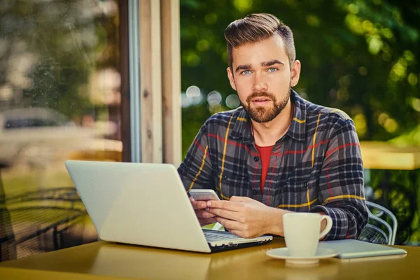 Όμορφος άνδρας χρησιμοποιώντας ένα φορητό υπολογιστή σε ένα καφέ — Φωτογραφία Αρχείου