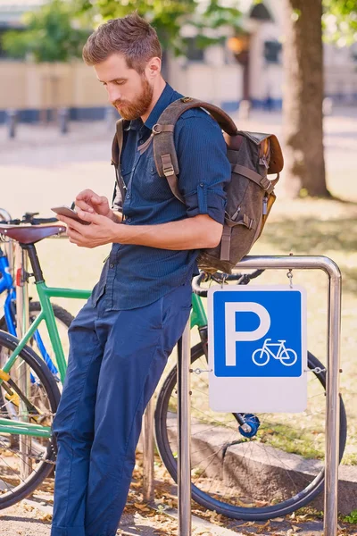 Hombre con smartphone cerca de bicicletas — Foto de Stock