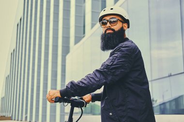 Elektrikli scooter üzerinde şık sakallı adam