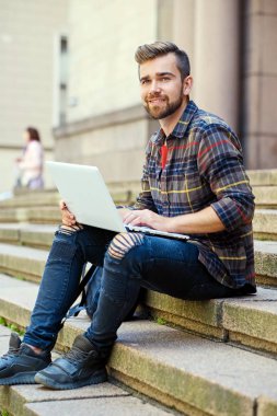 Casual bearded male using a laptop. clipart