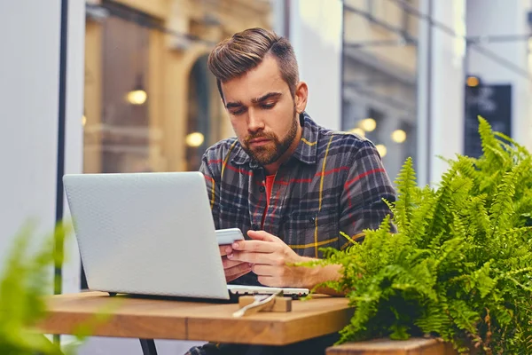 Bir kafede bir dizüstü bilgisayar kullanan adam