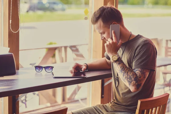 Man met de getatoeëerde arm gesprekken door smartphone — Stockfoto