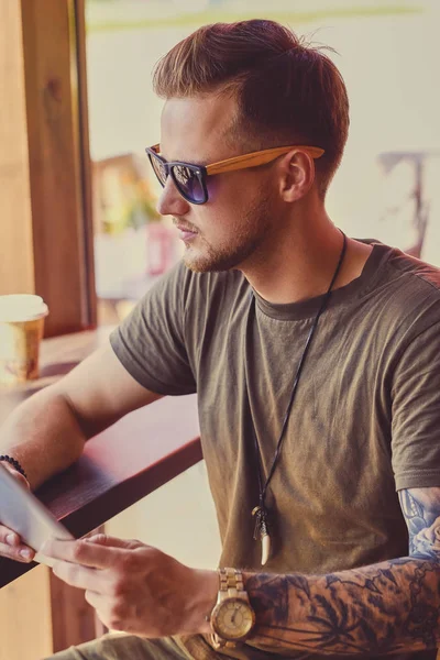 Ο τύπος σε γυαλιά ηλίου, χρησιμοποιώντας ένα tablet Pc — Φωτογραφία Αρχείου
