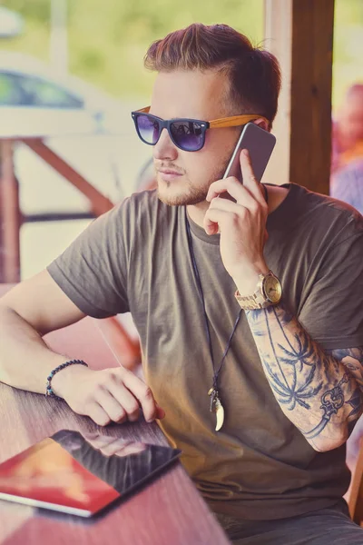 Dövmeli kolu görüşmeler yanında smartphone ile adam 